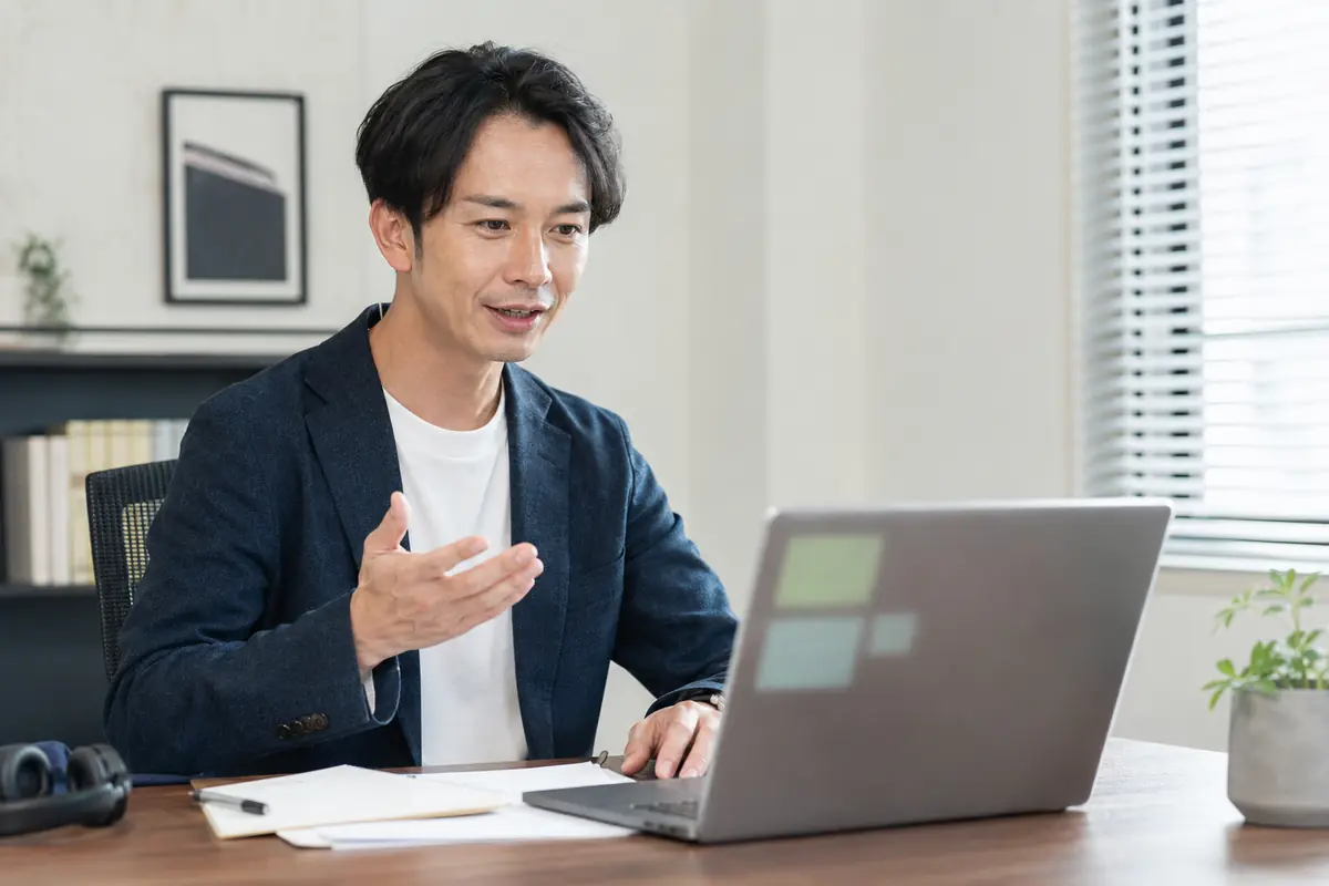 ノートパソコンでオンライン会議をする会社員