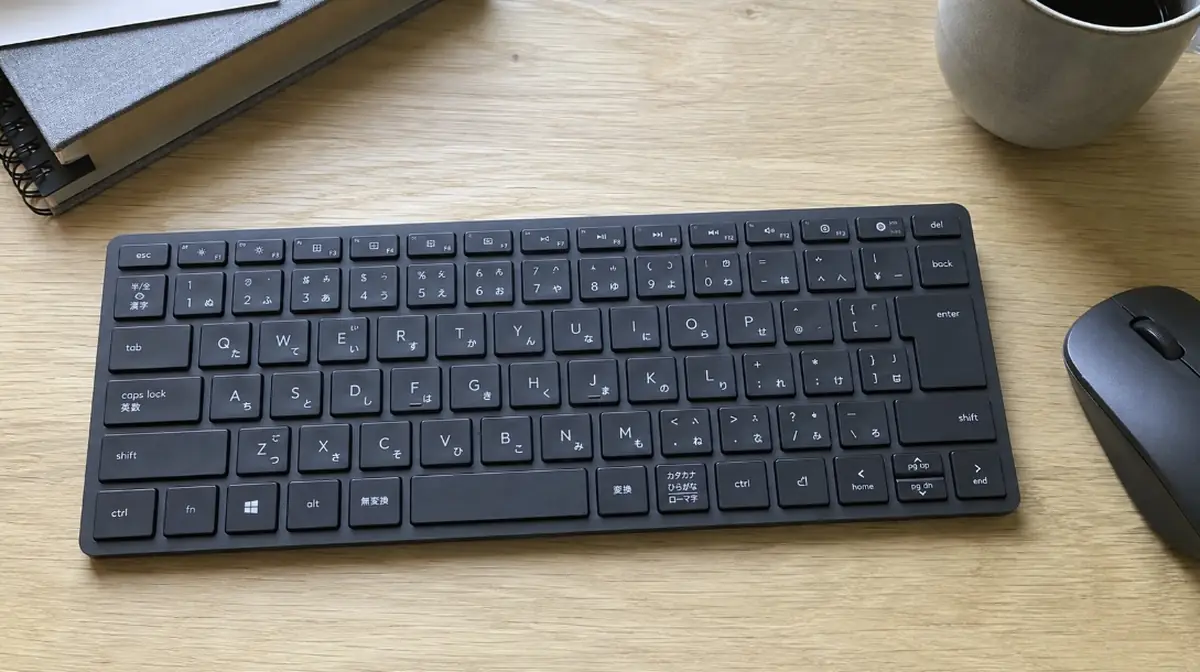 木製のデスクに置かれた日本語配列のキーボードとマウス
